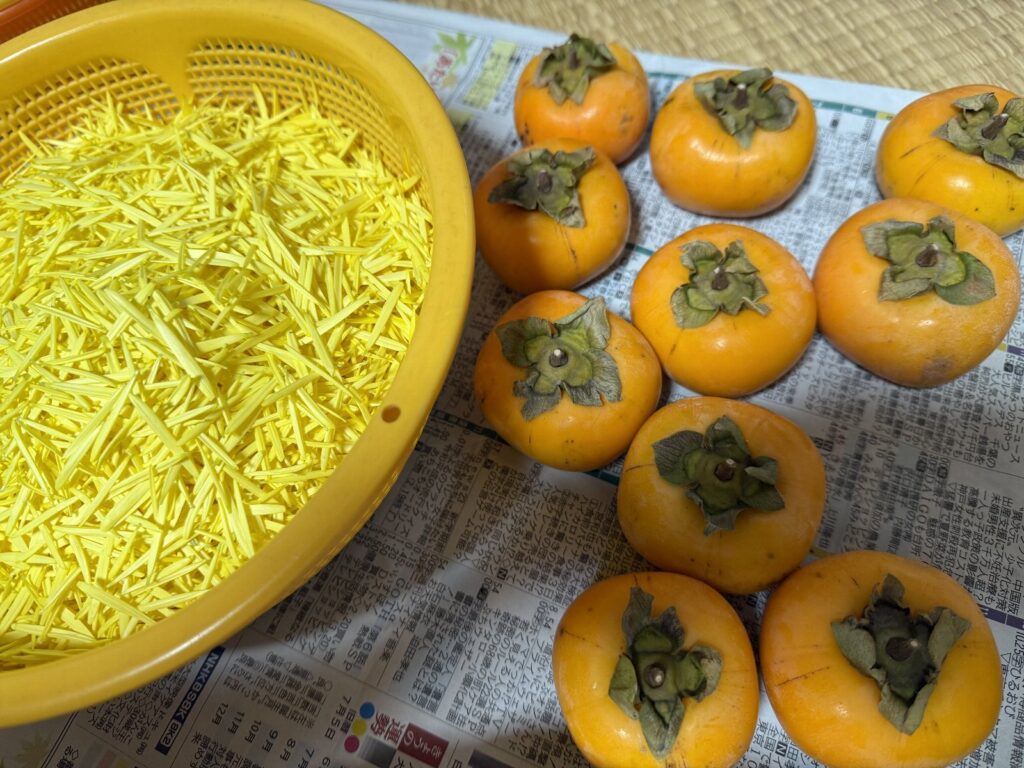 渋が抜けて食べれるようになった柿とザルの中にたくさん入っている散らされた食用菊｜天童市バリューハウスブログ用